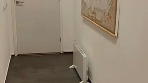 A hallway with a white door, a radiator, and a map on the wall.