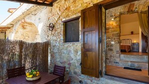 A stone-walled room with a wooden door, a window, and a table with chairs. - Romantic Stay Near Velia (Ascea)