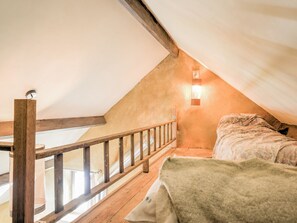 A bedroom with a wooden ceiling, a bed with a patterned blanket, and a nightstand. - Holiday Home in Philippeville With Garden (Philippeville)