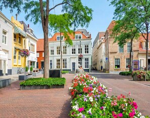 Una calle con arquitectura europea tradicional, jardineras con flores y cielo despejado.