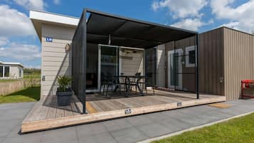 A modern house with a covered patio, a dining area, and a large window.