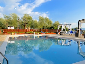 A swimming pool with lounge chairs and a pergola. - Belvilla by OYO Il Nido (Castelfranco Piandisco)