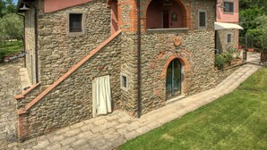 A stone building with a red roof, a small balcony, and a door with a glass window. - Belvilla by OYO Il Nido (Castelfranco Piandisco)
