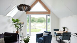 Un intérieur moderne avec un plafond en pente, un coin repas avec une table et des chaises, et un espace détente avec un canapé et des fauteuils.