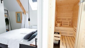 Une chambre à coucher avec un lit, une table de chevet, une lampe suspendue et une fenêtre.