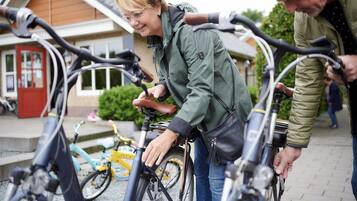 A person adjusting a bicycle in an outdoor setting with a building in the background.