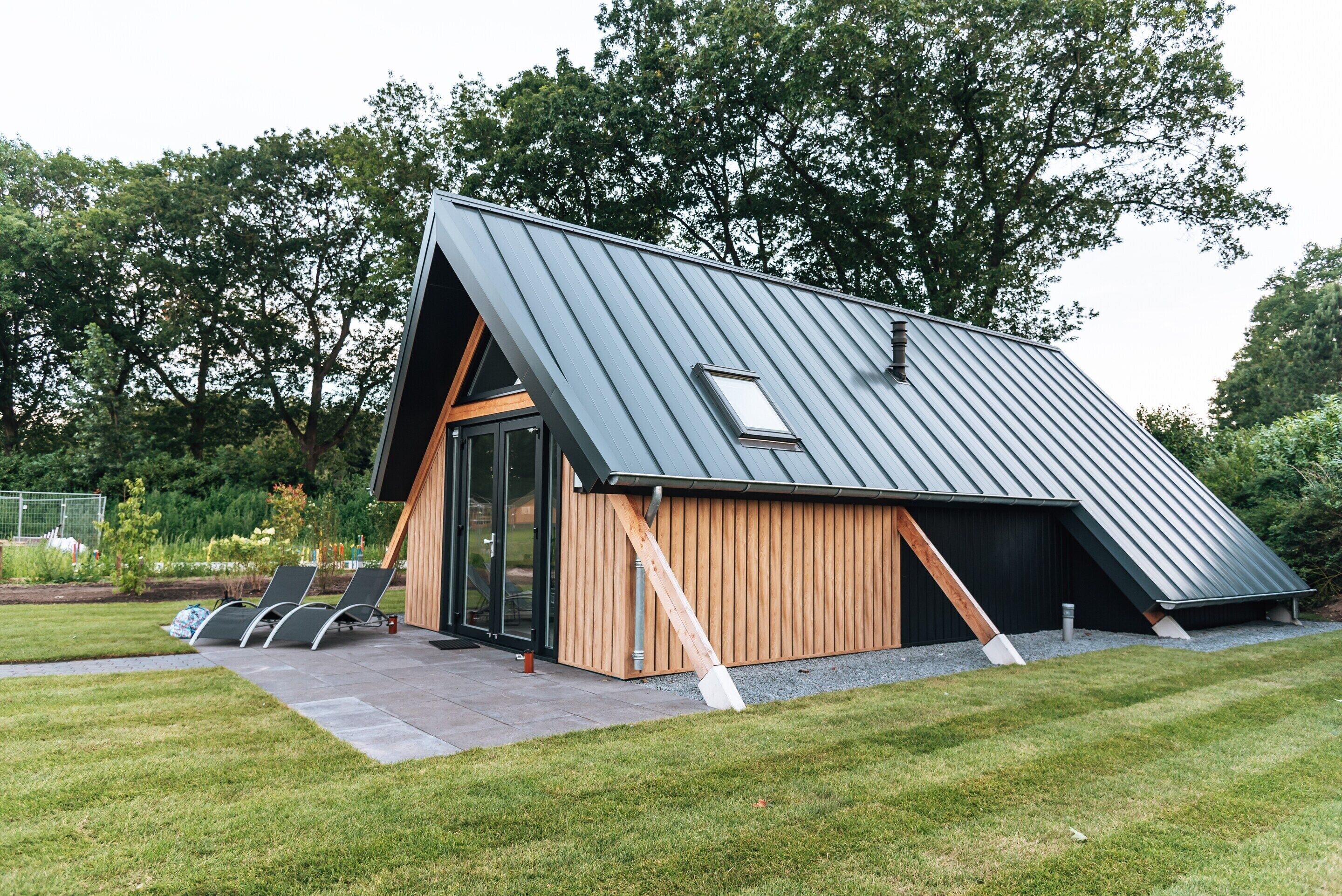 Un bâtiment moderne doté d’un toit en pente, de murs extérieurs en bois et d’une entrée avec une porte en verre.
