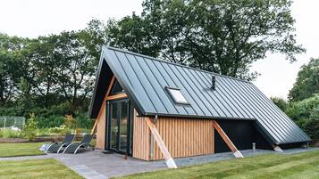 Un bâtiment moderne doté d’un toit en pente, de murs extérieurs en bois et d’une entrée avec une porte en verre.