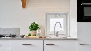 Une cuisine moderne avec des armoires blanches, un évier en acier inoxydable et un four encastré.