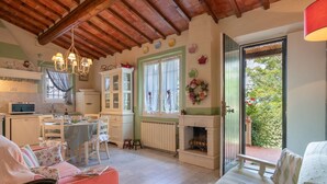 A cozy kitchen with a dining area, a fireplace, and a view of the garden. - Belvilla by OYO Selvatello Villino Trilo (Casole d'Elsa)