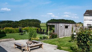 A rustic outdoor seating area with a fire pit, wooden tables, and chairs. - Pretty Farmhouse in Houffalize With Courtyard (Houffalize)