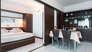 Ein modernes Hotelzimmer mit Bett, Nachttisch und einem Essbereich mit Stühlen und Tisch.