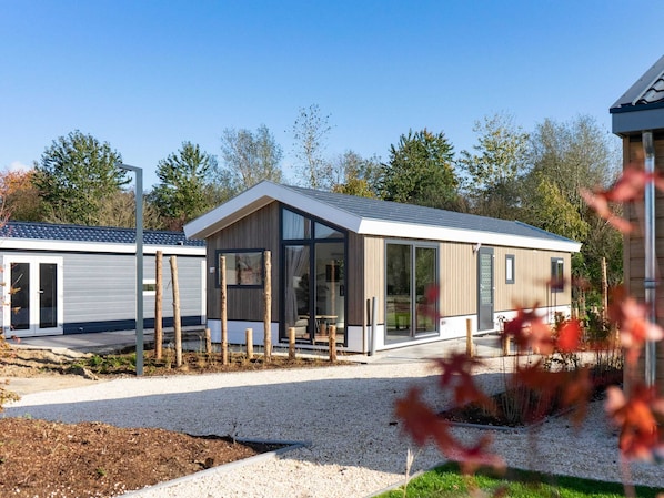A modern, single-story building with a sloped roof, large glass windows, and a gravel driveway.