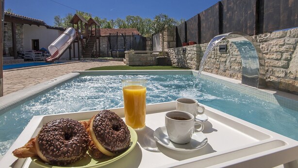 A poolside breakfast tray with two chocolate donuts, a glass of orange juice, and two cups of coffee. - Perfect for Children, Garden With Pool, Playground and Walk in Whirlpool (Tinjan)