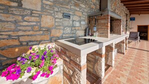 A stone wall with a built-in bar area, a hanging rack with cleaning tools, and a chair. - Perfect for Children, Garden With Pool, Playground and Walk in Whirlpool (Tinjan)