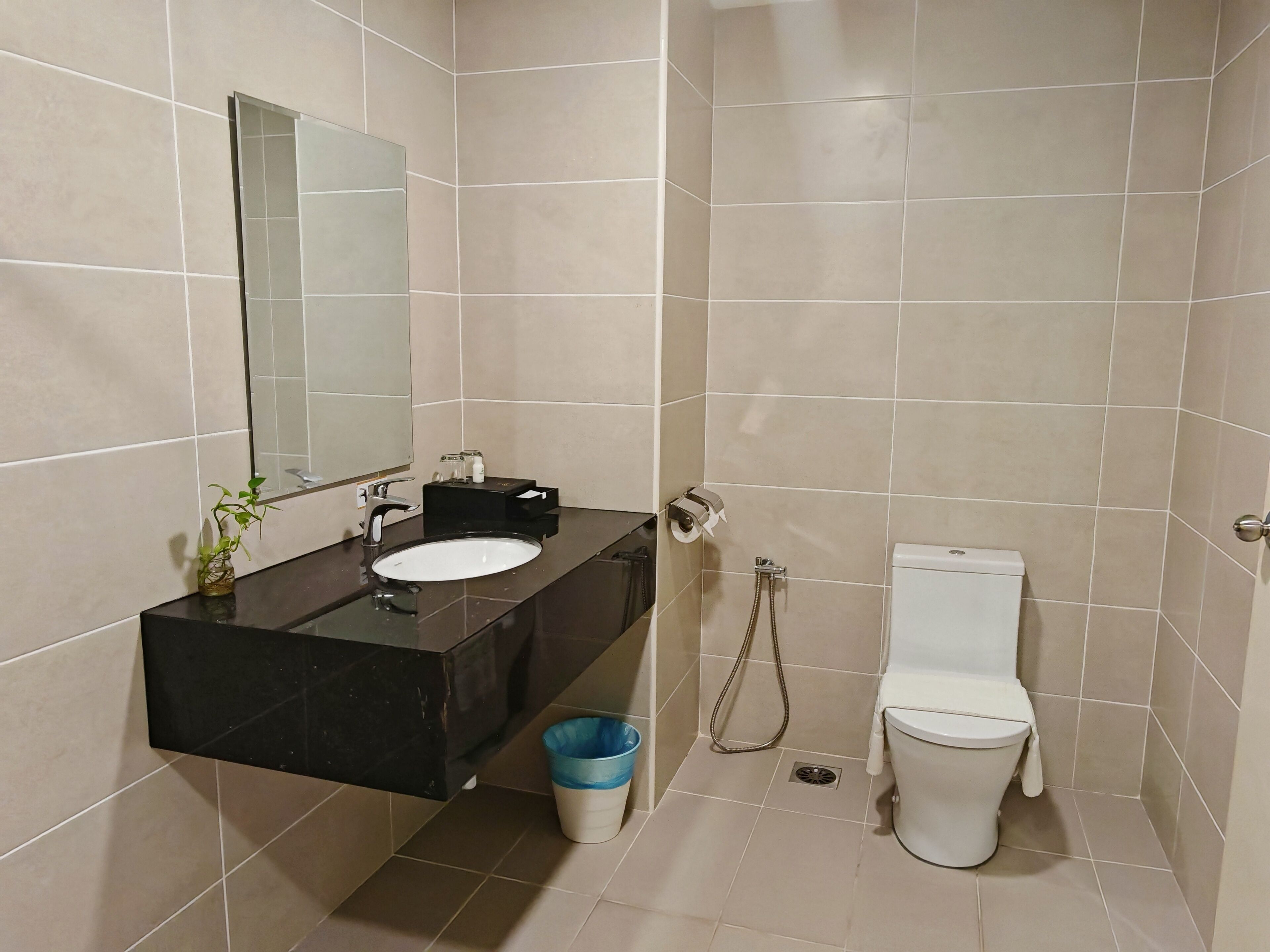 Een badkamer met een zwart wastafel, spiegel, toilet en douche.