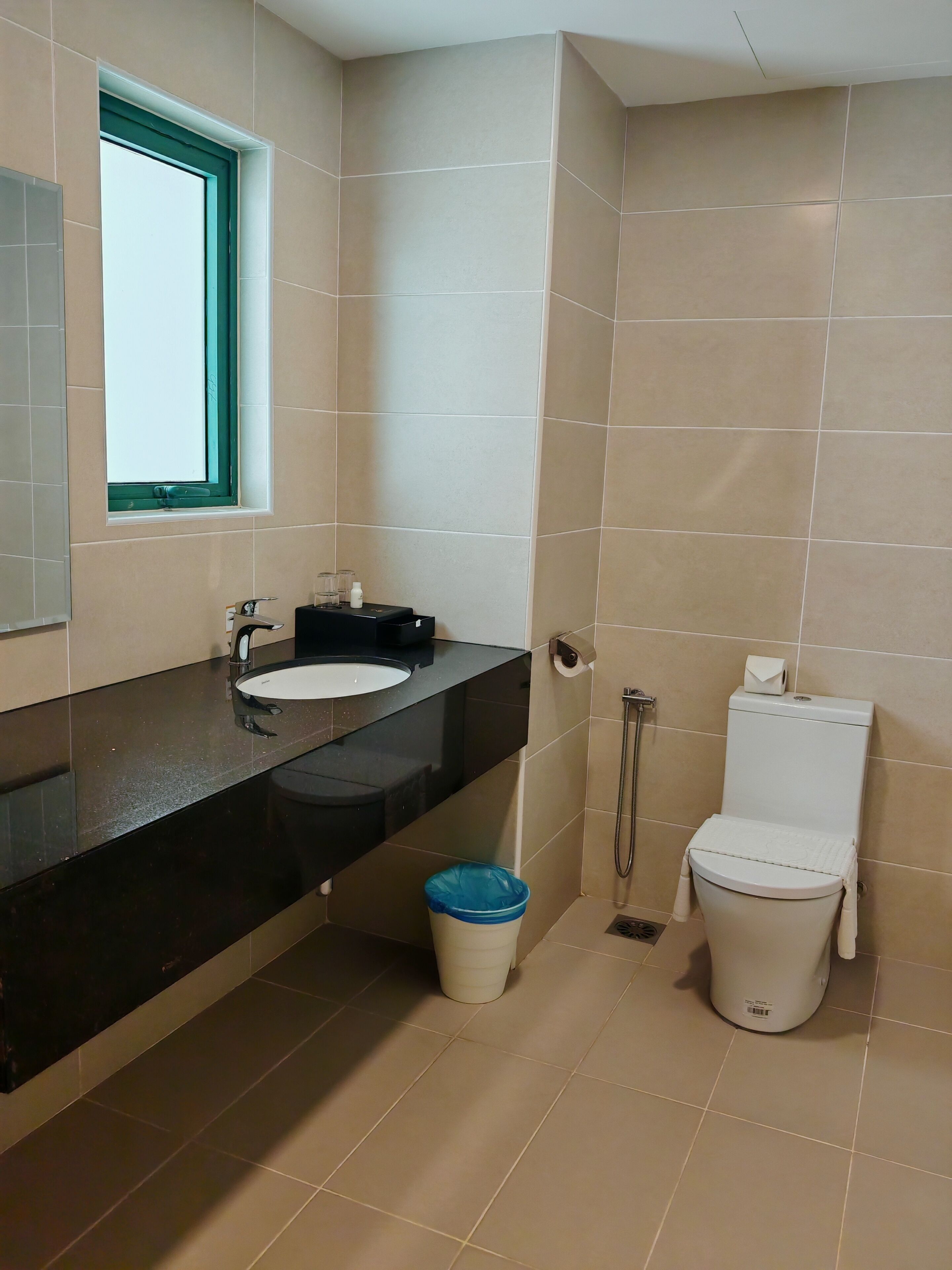 Un baño con lavamanos, inodoro y ventana.