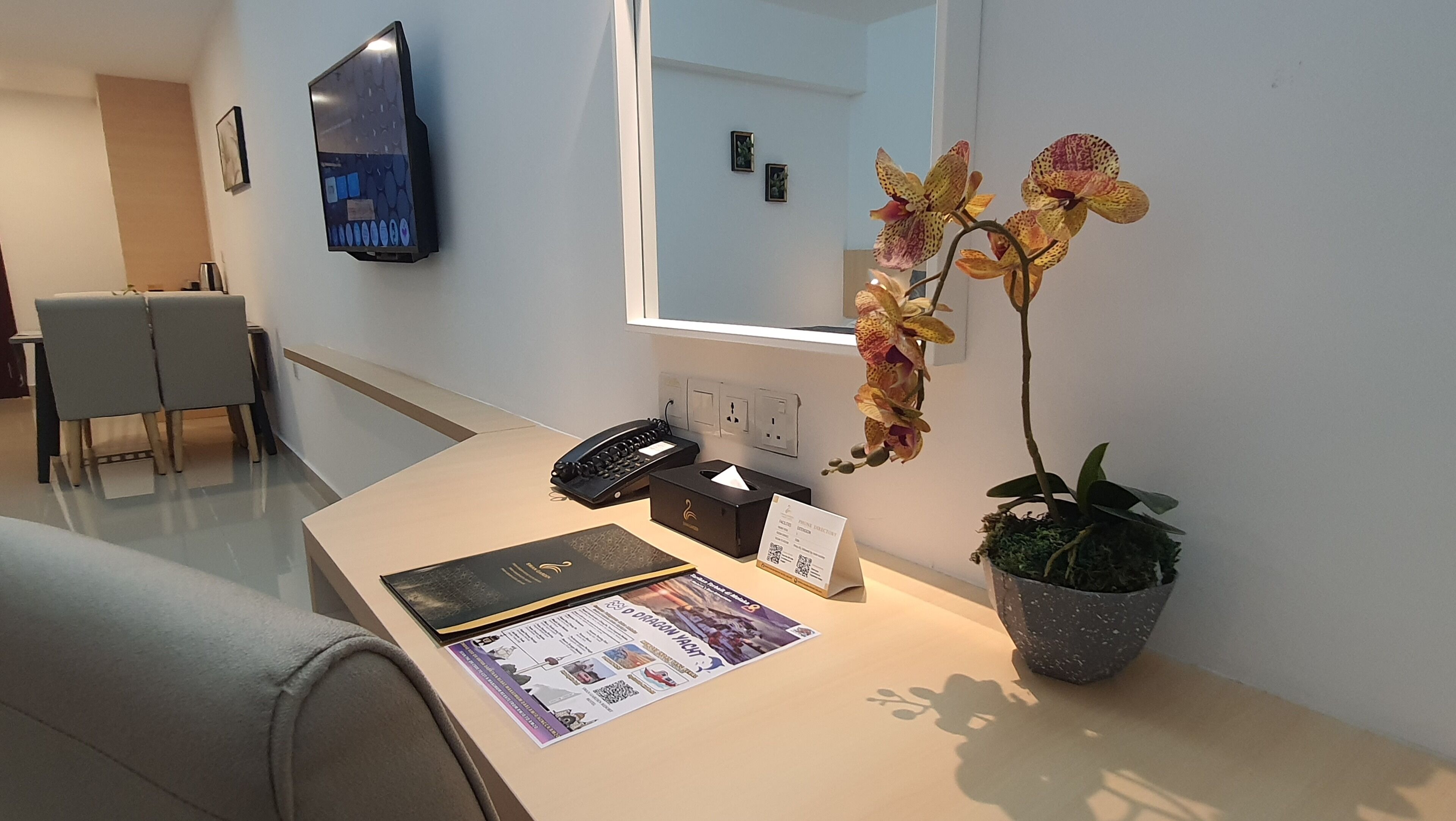 A reception desk with a telephone, a tissue box, a guest directory, and a potted orchid.