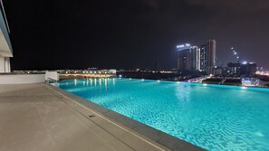 A nighttime view of a swimming pool with city lights in the background. - Swan Garden Resort Hotel (Malacca City)
