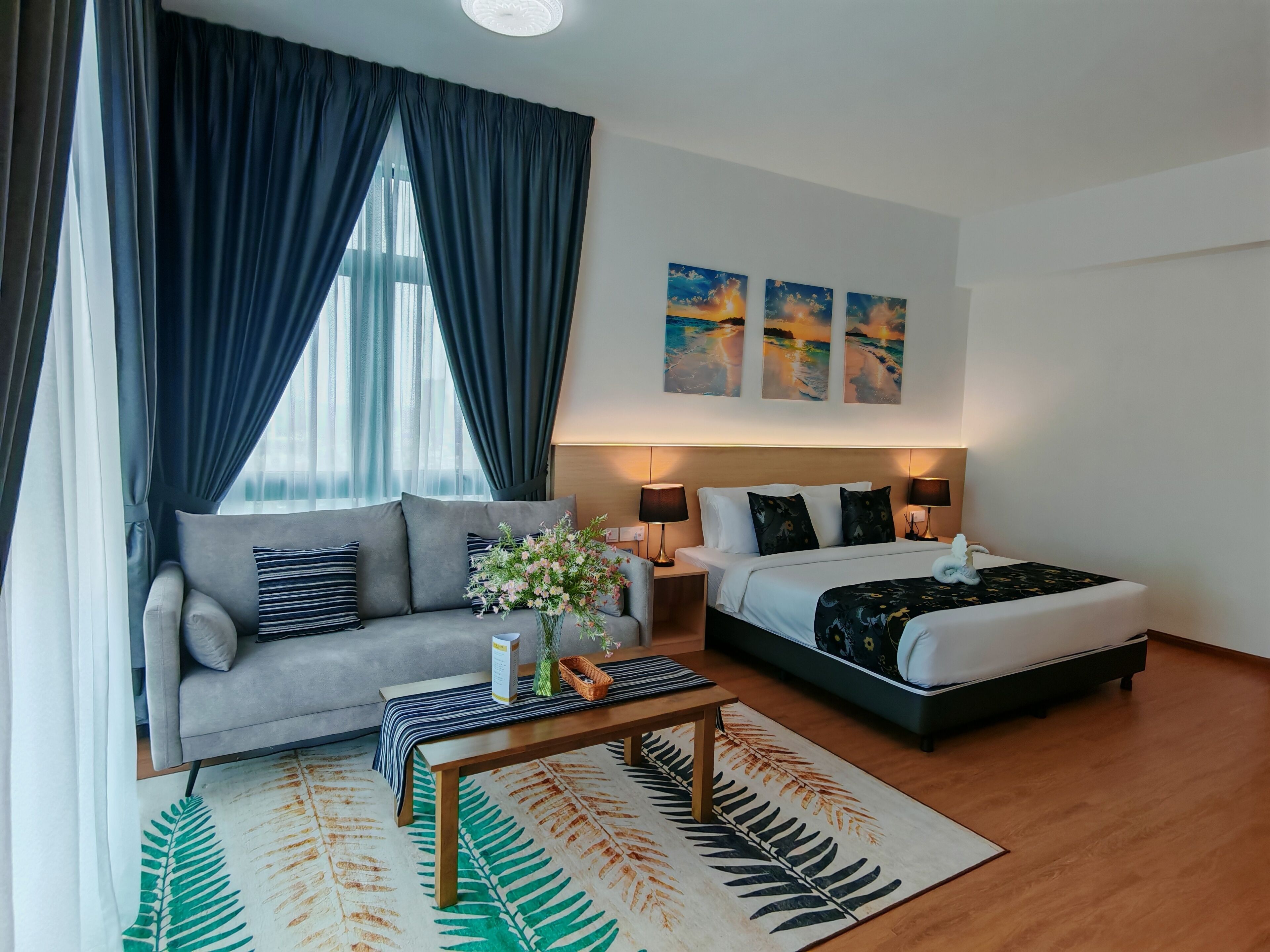 A hotel room with a sofa, a bed, a coffee table, and artwork on the wall.