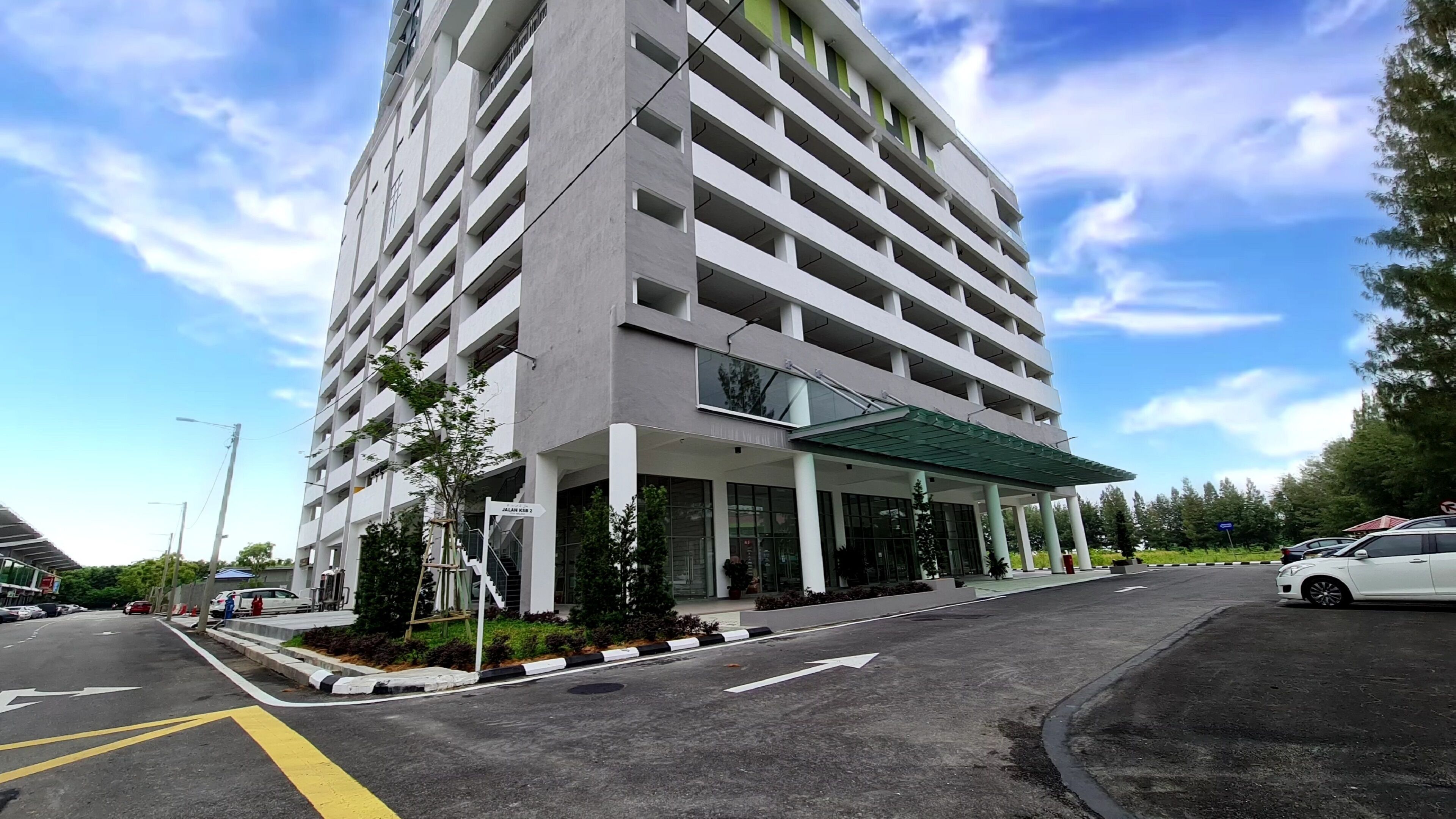 A multi-story parking garage with a covered entrance and a sign indicating 'JALAN KAWAR 2'.