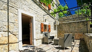 Un bâtiment en pierre doté d’un patio aménagé avec du mobilier d’extérieur et un sol en pierre.