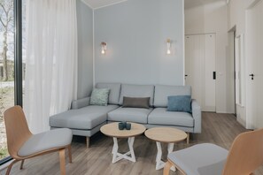 A modern living room with a grey sectional sofa, two round wooden tables, and light wood flooring. - Luxury Lodge with 2 Bathrooms near Markermeer (Wijdenes)