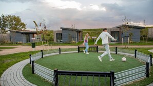 A circular outdoor area with artificial turf, surrounded by a metal fence and benches. - Luxury Lodge with 2 Bathrooms near Markermeer (Wijdenes)