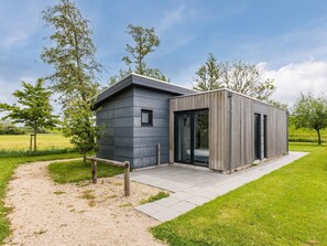 Un bâtiment moderne, avec un chemin de gravier menant à l’entrée, entouré de verdure.