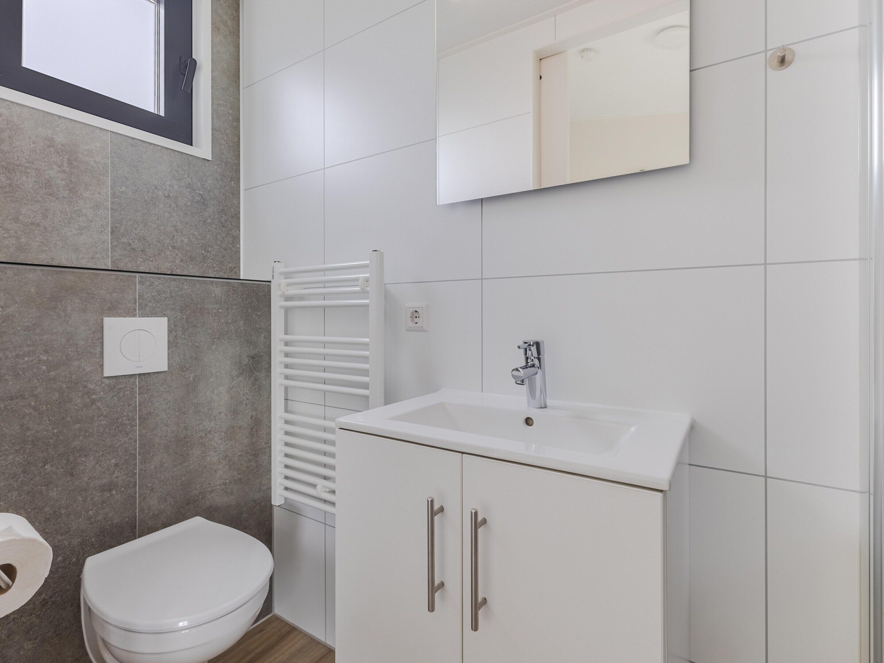 Un baño con inodoro, lavabo, espejo y toallero.
