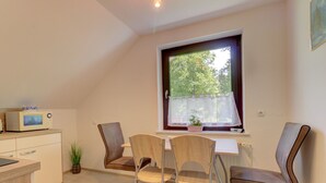 A small kitchen with a microwave, a window with a view of trees, and two chairs at a table. - Charming Apartment in Bled Near Lake (Bled)
