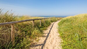 A sandy path with wooden railings, surrounded by grass and leading to a beach. - Apartment in Egmond by the Beach (Egmond aan Zee)