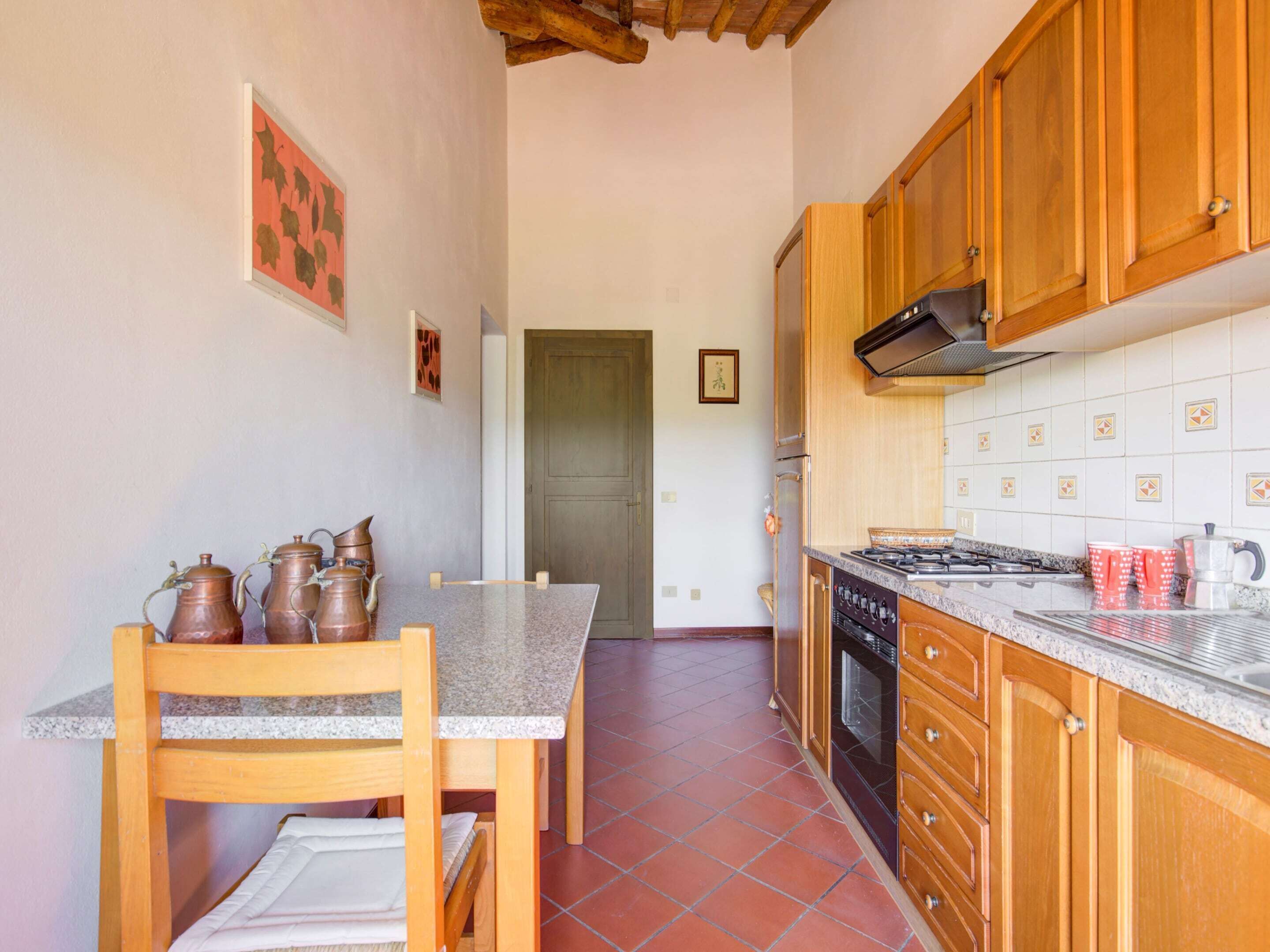 A kitchen with wooden cabinets, a tiled backsplash, a stove, and a dining area with a table and chairs.