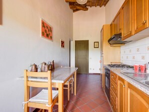 Una cocina con armarios de madera, salpicadero de azulejos y un comedor con mesa y sillas.