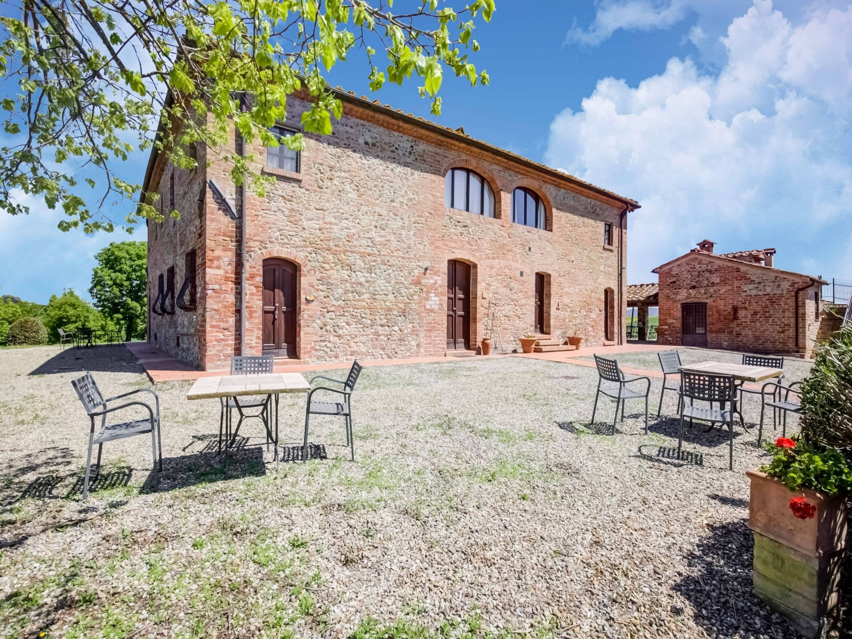 A rustic stone building with outdoor seating and a gravel courtyard.