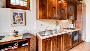 A kitchen with wooden cabinets, a double sink, and a stove. - Belvilla by OYO Piandigoro Intero (Radicofani)