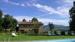 A stone building with a tiled roof, a swimming pool, and lounge chairs. - Belvilla by OYO Piandigoro Intero (Radicofani)