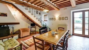 A dining area with a wooden table, chairs, and a staircase with exposed beams. - Belvilla by OYO Piandigoro Intero (Radicofani)