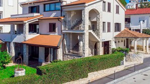 Un immeuble à plusieurs étages, doté d’une façade en pierre, d’un balcon et d’un toit recouvert de tuiles.