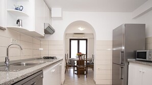 Une cuisine moderne avec des armoires blanches, un comptoir en granit, un lave-vaisselle intégré, un réfrigérateur en acier inoxydable et un four à micro-ondes.