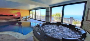 A spa area with a hot tub and a pool, large windows with a view of the sea, and a sunset painting on the wall. - Divine Holiday Home in Giosa Marea with Sauna & Hot Tub (Gioiosa Marea)