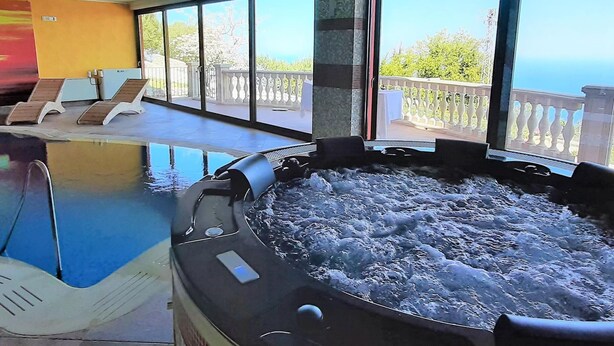 Un bain à remous dans une pièce dotée de grandes fenêtres, une piscine et des chaises longues.