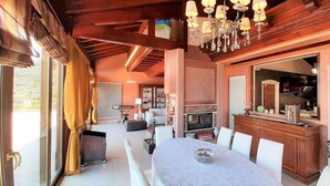 Un vaste espace dédié à la salle à manger, avec une grande table et des chaises, un lustre et une vue sur l’extérieur.