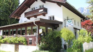 Un bâtiment à deux étages doté d’un balcon, d’une enseigne indiquant « Café Rosmarie » et ayant une chaîne de montagnes en arrière-plan.