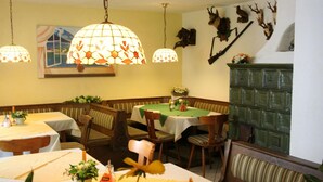 L’intérieur d’un restaurant, avec des banquettes, des tables, des lampes suspendues et des têtes d’animaux fixées aux murs.