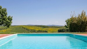A clear blue swimming pool with a view of green hills and a tree-lined area. - Tuscan Farmhouse in Peccioli with Swimming Pool near Lakes (Peccioli)