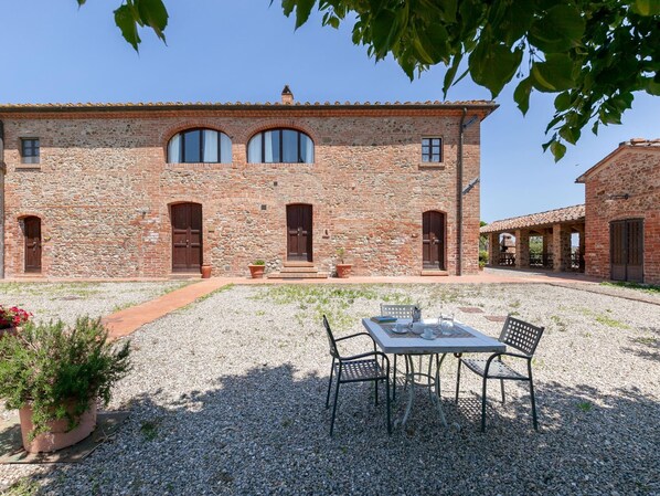 A stone building with a courtyard, a table with chairs, and potted plants.