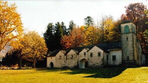 Un bâtiment rustique doté d’une tour, entouré d’arbres aux feuilles d’automne.
