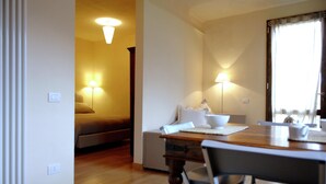 Une chambre d’hôtel avec une table à manger en bois, deux chaises, un canapé et deux lampes de chevet.