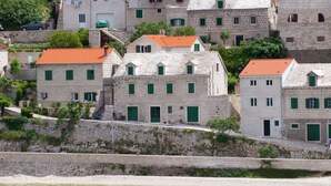 A coastal village with stone buildings, green shutters, and a clear view of the sea. - Beautiful Holiday Home on the Island Brac, With the Sea and a Small Beach in Front of the Door (Pucisca)